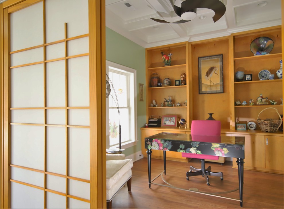 Diseño de despacho asiático de tamaño medio sin chimenea con biblioteca, paredes verdes, suelo vinílico, escritorio independiente y suelo marrón