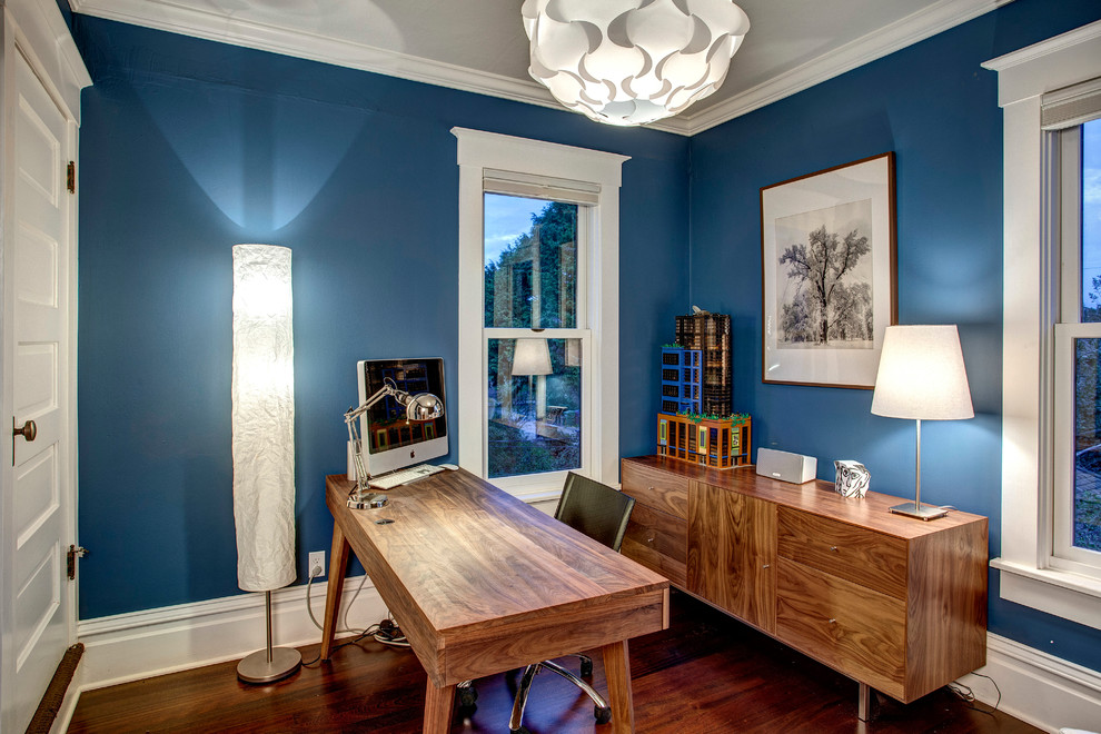 На фото: кабинет среднего размера в стиле кантри с синими стенами, темным паркетным полом и отдельно стоящим рабочим столом с