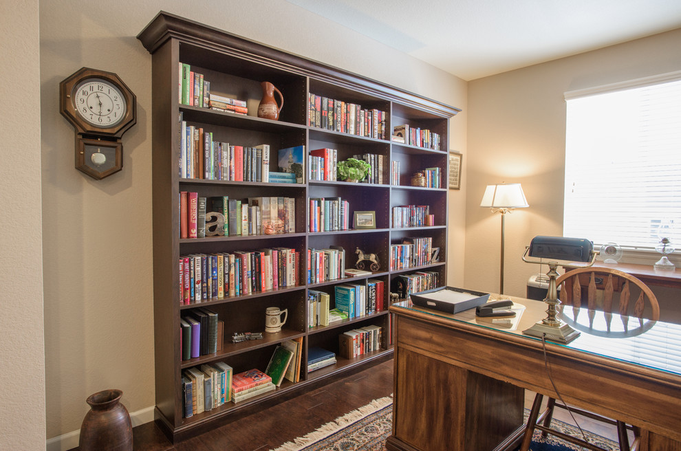 Ejemplo de despacho clásico pequeño con paredes beige, suelo de madera oscura y escritorio independiente