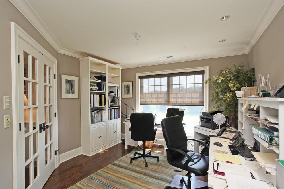 This is an example of a country study in New York with dark hardwood flooring, no fireplace, a freestanding desk and grey walls.