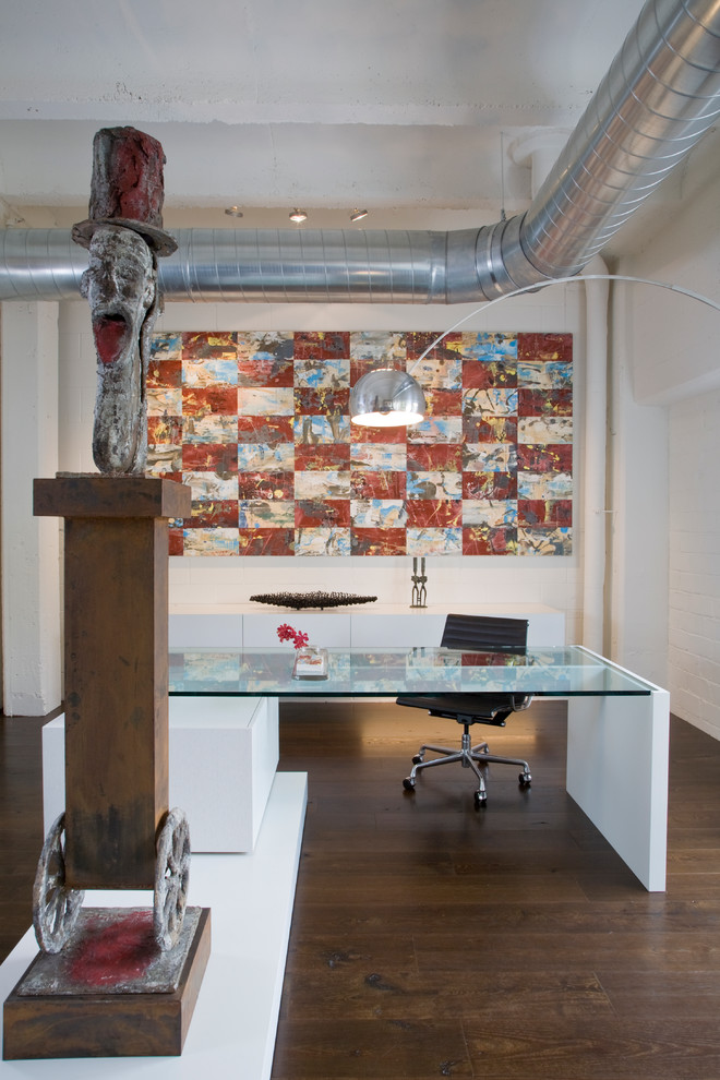 Bild på ett industriellt arbetsrum, med vita väggar, mörkt trägolv och ett fristående skrivbord