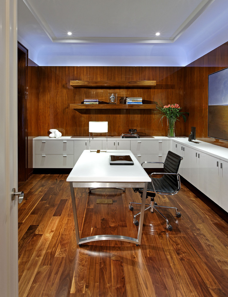 Пример оригинального дизайна: большое рабочее место в современном стиле с темным паркетным полом, отдельно стоящим рабочим столом, коричневыми стенами и коричневым полом без камина