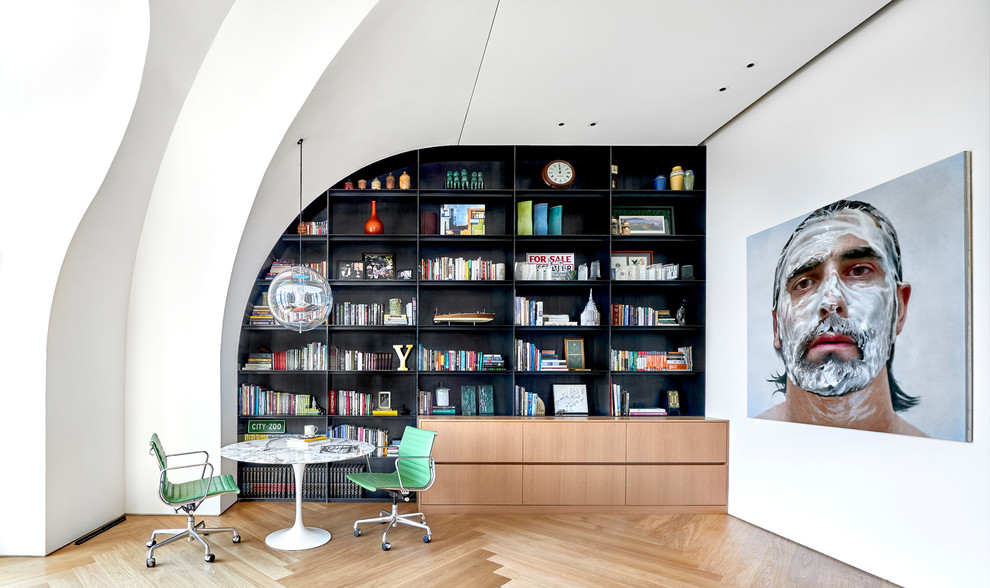 Aménagement d'un grand bureau contemporain avec une bibliothèque ou un coin lecture, un mur blanc, parquet clair et un bureau indépendant.
