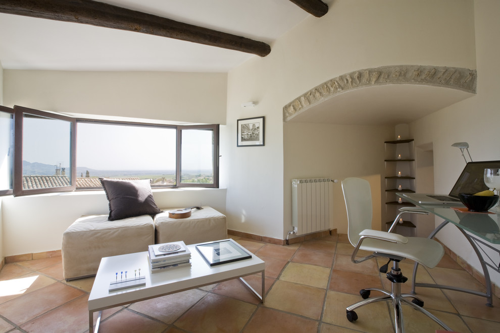 Modelo de despacho mediterráneo con paredes blancas, escritorio independiente y suelo de baldosas de terracota