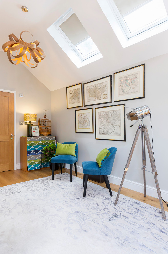 This is an example of a large contemporary home studio in Surrey with grey walls, light hardwood flooring, a freestanding desk, brown floors, a vaulted ceiling and wallpapered walls.