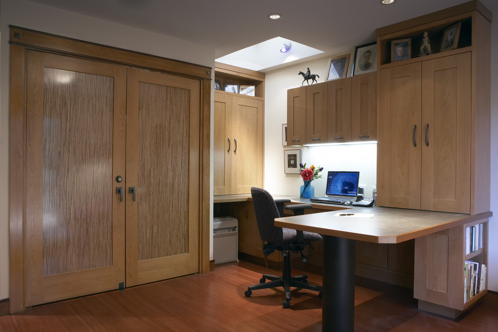 Foto de despacho actual con paredes blancas, suelo de madera en tonos medios y escritorio empotrado