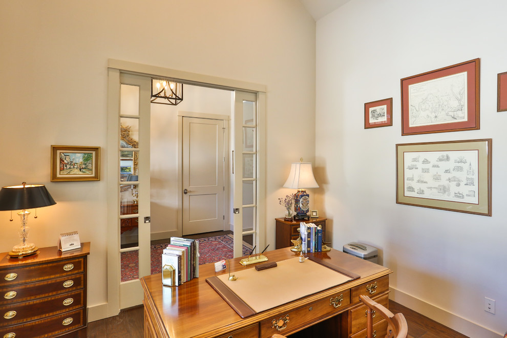 Foto de despacho clásico de tamaño medio sin chimenea con paredes blancas, suelo de madera oscura, escritorio independiente y suelo marrón