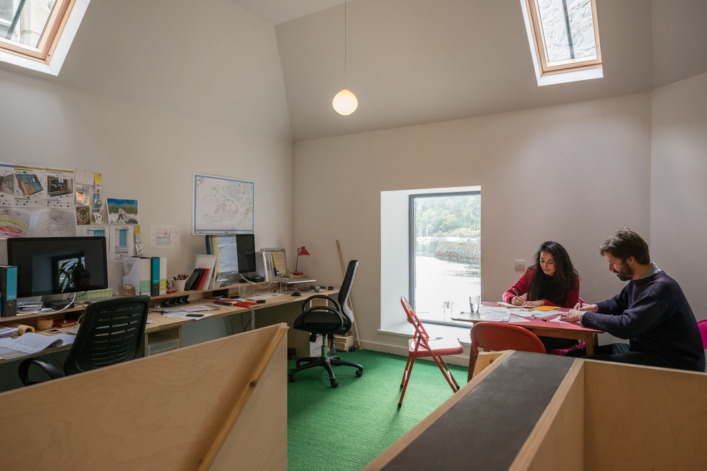 This is an example of a small contemporary home studio in Other with white walls, carpet, a built-in desk and green floors.