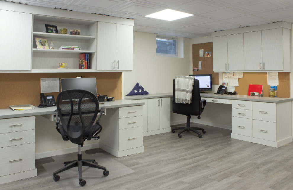 Inredning av ett klassiskt mellanstort arbetsrum, med vita väggar, laminatgolv, ett inbyggt skrivbord och grått golv