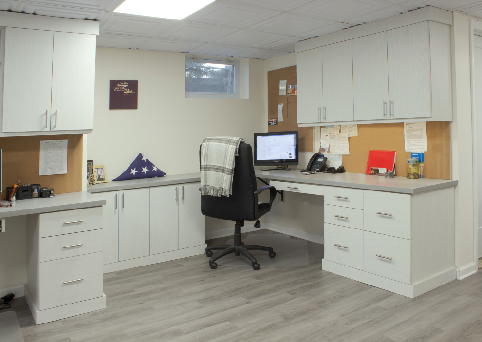 Inredning av ett klassiskt mellanstort arbetsrum, med vita väggar, laminatgolv, ett inbyggt skrivbord och grått golv