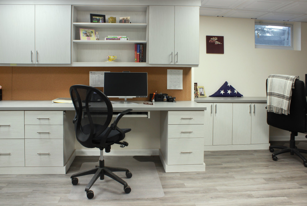 Immagine di uno studio tradizionale di medie dimensioni con pareti bianche, pavimento in laminato, scrivania incassata e pavimento grigio