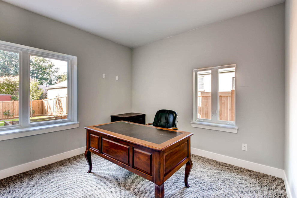Diseño de despacho de estilo americano grande con paredes grises, moqueta y escritorio independiente