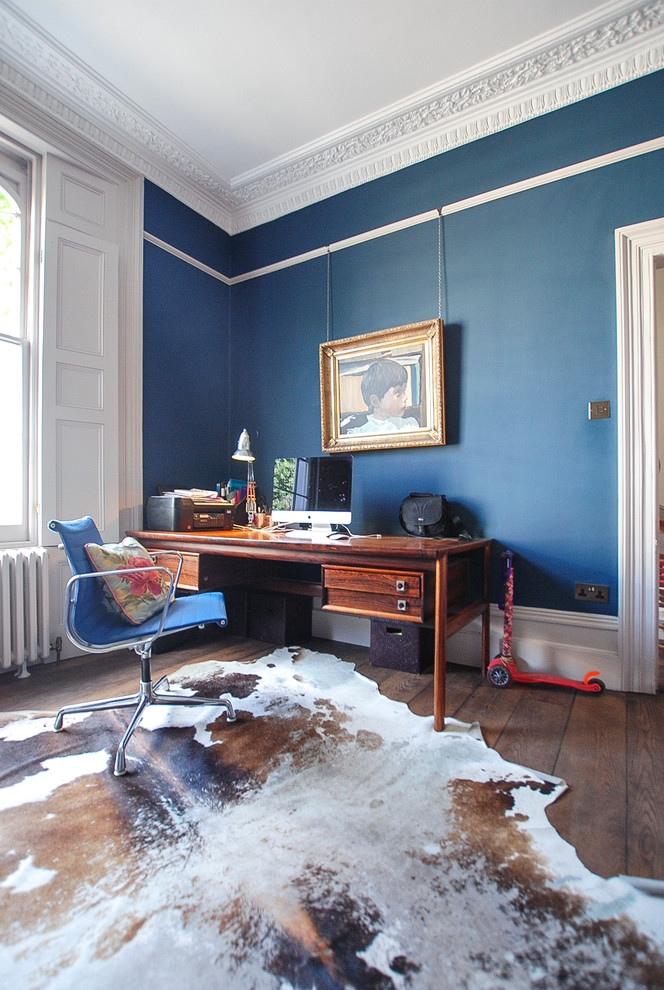 Idee per un ufficio minimal di medie dimensioni con pareti blu, parquet scuro e scrivania autoportante