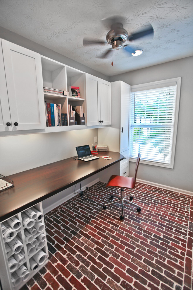 Foto på ett litet amerikanskt arbetsrum, med grå väggar, tegelgolv och ett inbyggt skrivbord