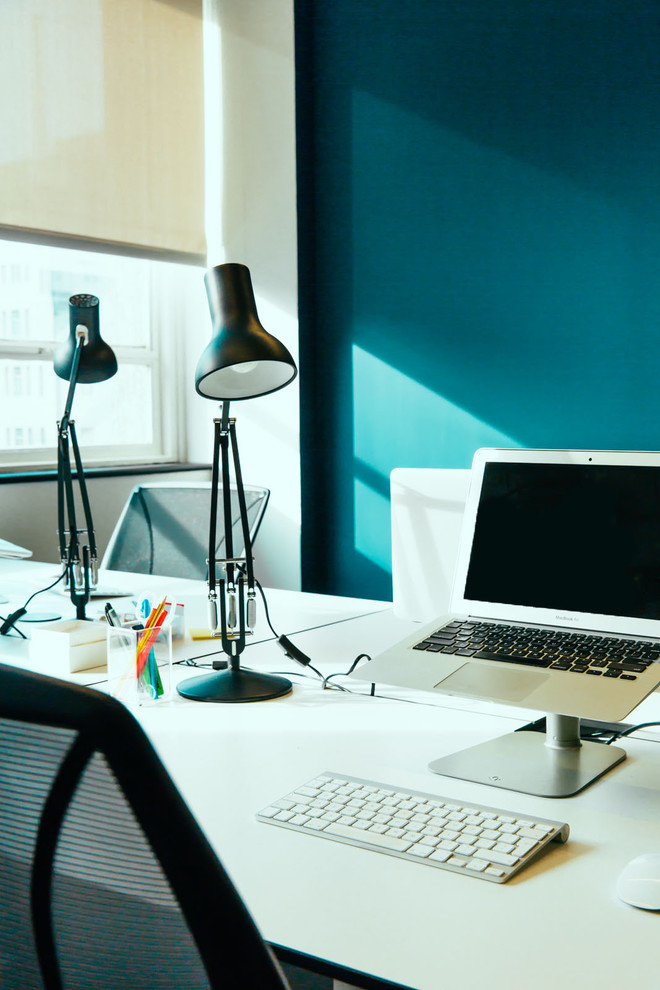 Immagine di un ufficio contemporaneo di medie dimensioni con pareti blu, moquette e scrivania autoportante