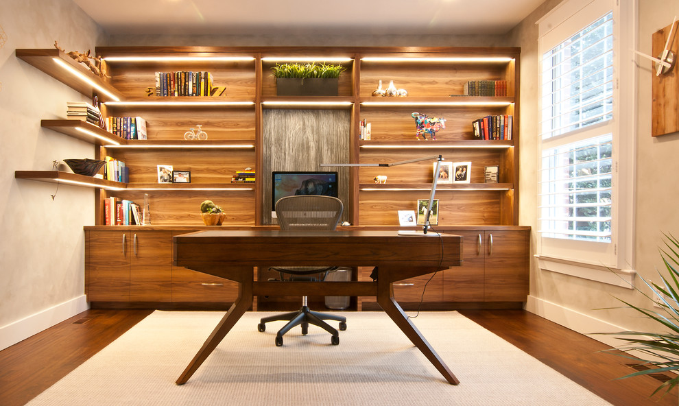 Idéer för att renovera ett mellanstort funkis hemmabibliotek, med beige väggar, mellanmörkt trägolv och ett fristående skrivbord