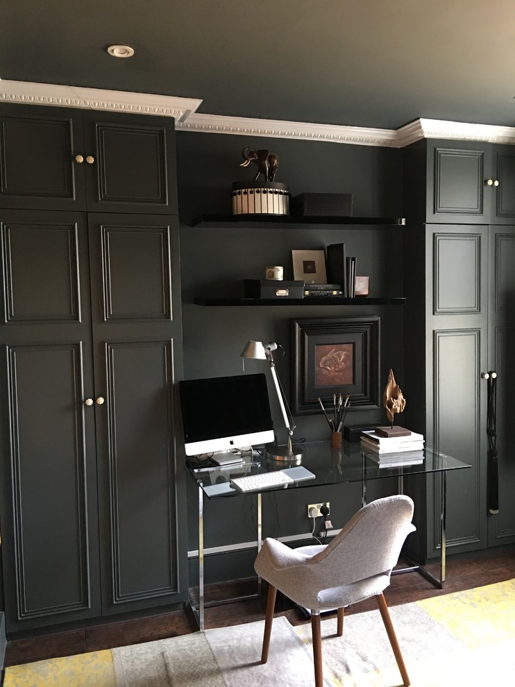 Modelo de despacho ecléctico de tamaño medio sin chimenea con paredes grises, suelo de madera oscura y escritorio independiente