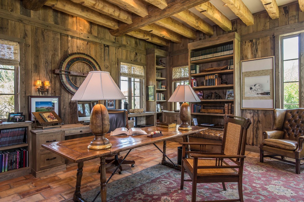 フェニックスにあるラグジュアリーな広いおしゃれな書斎 (茶色い壁、テラコッタタイルの床、暖炉なし、石材の暖炉まわり、自立型机) の写真