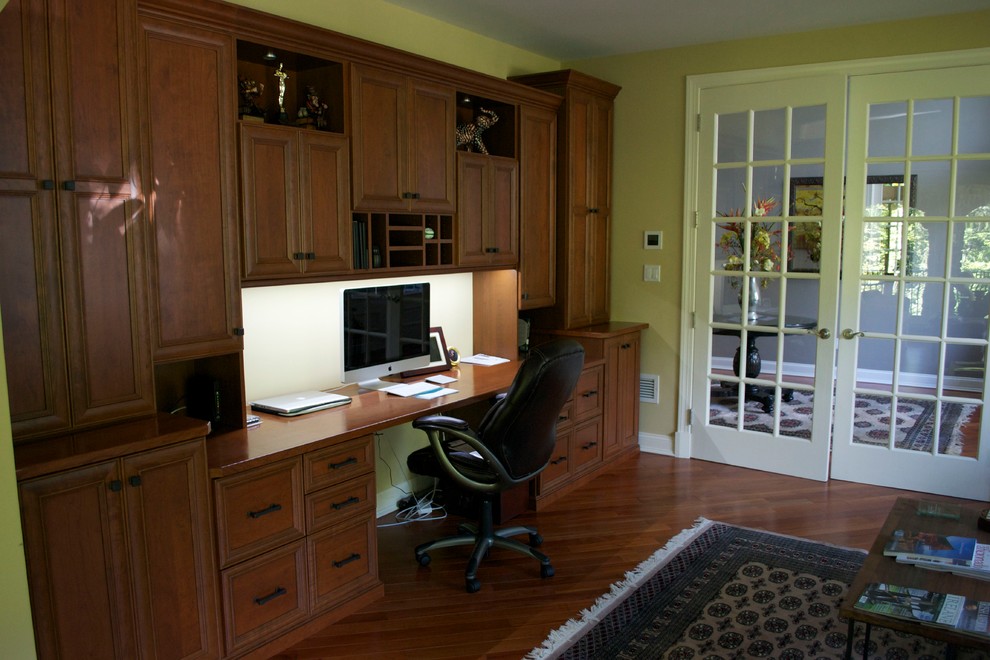 This is an example of a large traditional study in New York with medium hardwood flooring and a built-in desk.