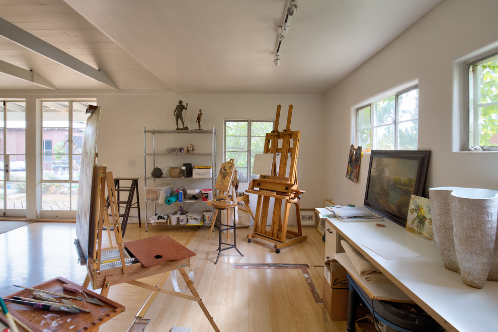 Large classic home studio in Santa Barbara with beige walls, light hardwood flooring, no fireplace and brown floors.