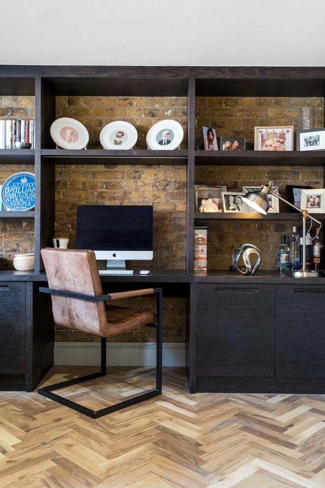 Small urban home office in London with beige walls, light hardwood flooring, a built-in desk and brown floors.