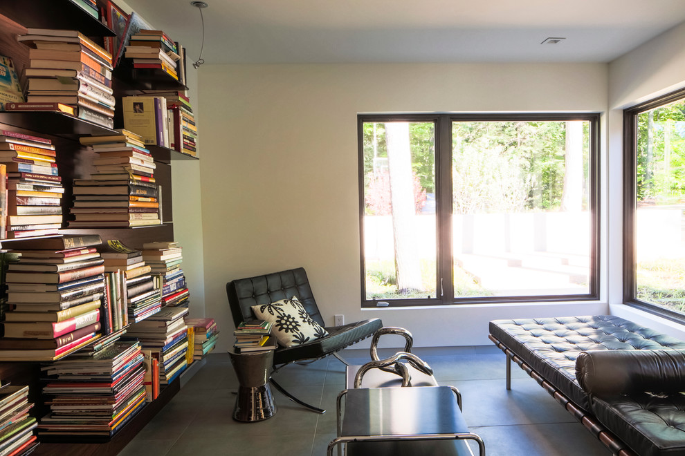 Bild på ett mellanstort funkis arbetsrum, med ett bibliotek, vita väggar och betonggolv