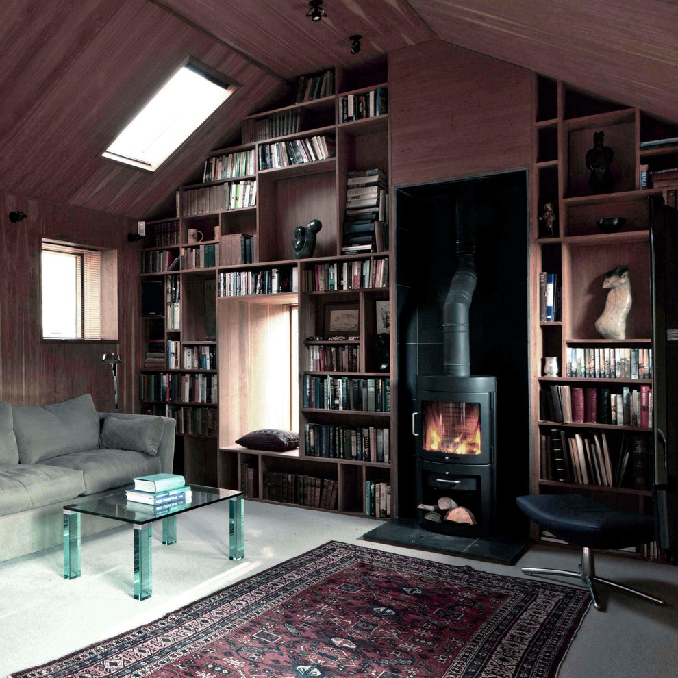 Idéer för ett litet modernt hemmabibliotek, med bruna väggar, heltäckningsmatta, en öppen vedspis, en spiselkrans i sten, ett fristående skrivbord och beiget golv