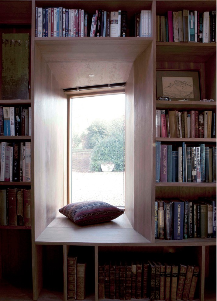 Ejemplo de despacho contemporáneo pequeño con biblioteca, paredes marrones, moqueta, estufa de leña, marco de chimenea de piedra, escritorio independiente y suelo beige