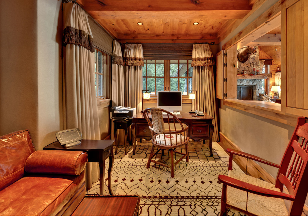 Rustik inredning av ett arbetsrum, med beige väggar, mellanmörkt trägolv och ett fristående skrivbord