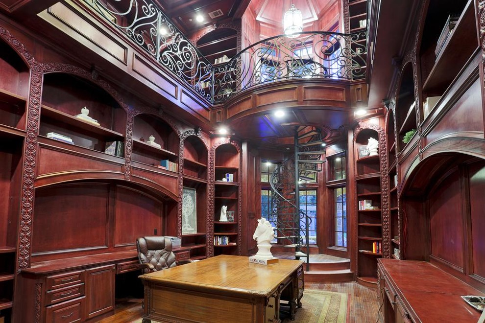 Inspiration för mycket stora klassiska hemmabibliotek, med bruna väggar, mellanmörkt trägolv och ett inbyggt skrivbord