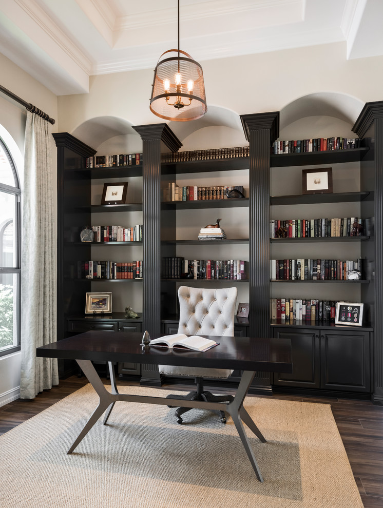 他の地域にあるトランジショナルスタイルのおしゃれなホームオフィス・書斎 (ライブラリー、ベージュの壁、自立型机、茶色い床) の写真
