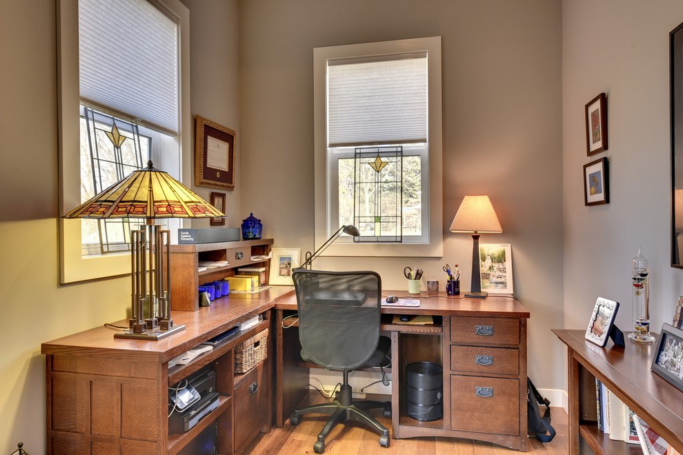 Cette photo montre un bureau craftsman avec un mur gris, un sol en bois brun et un bureau indépendant.
