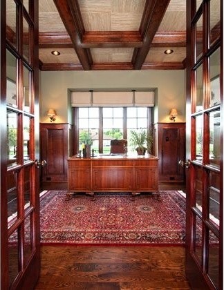 Bild på ett stort vintage hemmabibliotek, med gröna väggar, mellanmörkt trägolv, ett fristående skrivbord och brunt golv