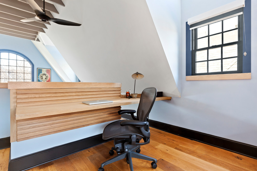 На фото: рабочее место среднего размера в стиле неоклассика (современная классика) с синими стенами, светлым паркетным полом, встроенным рабочим столом и коричневым полом без камина
