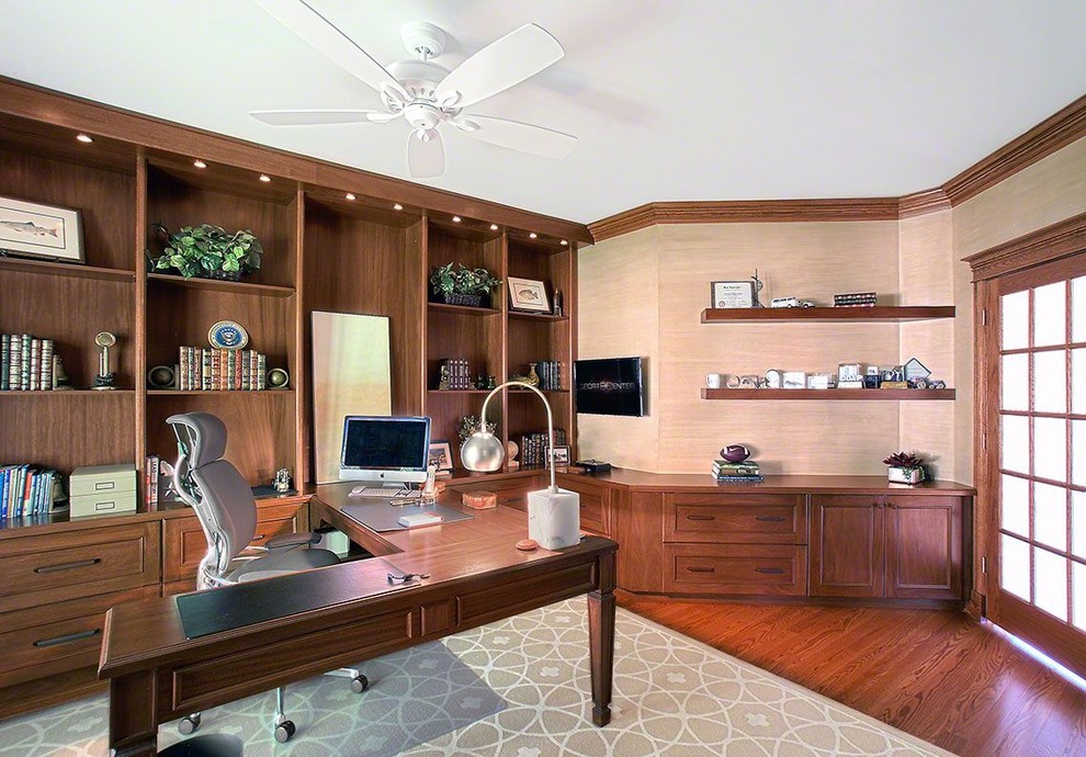 Klassisches Arbeitszimmer mit beiger Wandfarbe, braunem Holzboden, freistehendem Schreibtisch und braunem Boden in Chicago