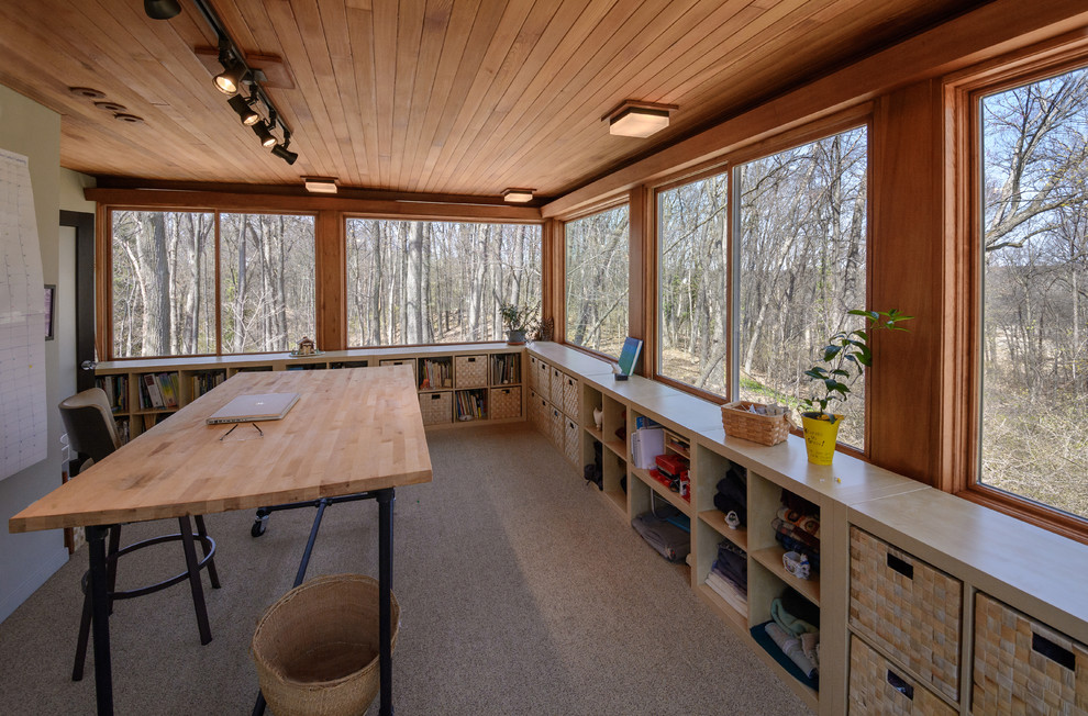 Foto på ett 50 tals hemmabibliotek, med beige väggar, heltäckningsmatta, ett fristående skrivbord och brunt golv