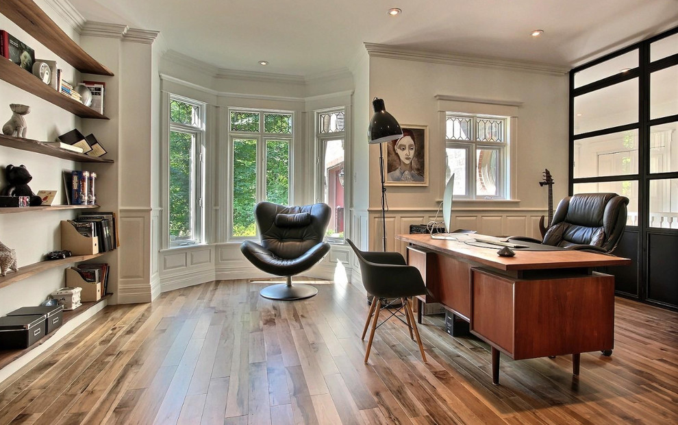 Mittelgroßes Modernes Arbeitszimmer ohne Kamin mit Arbeitsplatz, weißer Wandfarbe, braunem Holzboden, freistehendem Schreibtisch und braunem Boden in Montreal