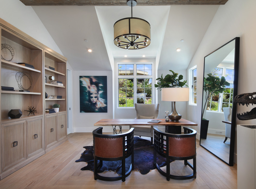 This is an example of a traditional home office in Orange County with white walls, light hardwood flooring, no fireplace and a freestanding desk.