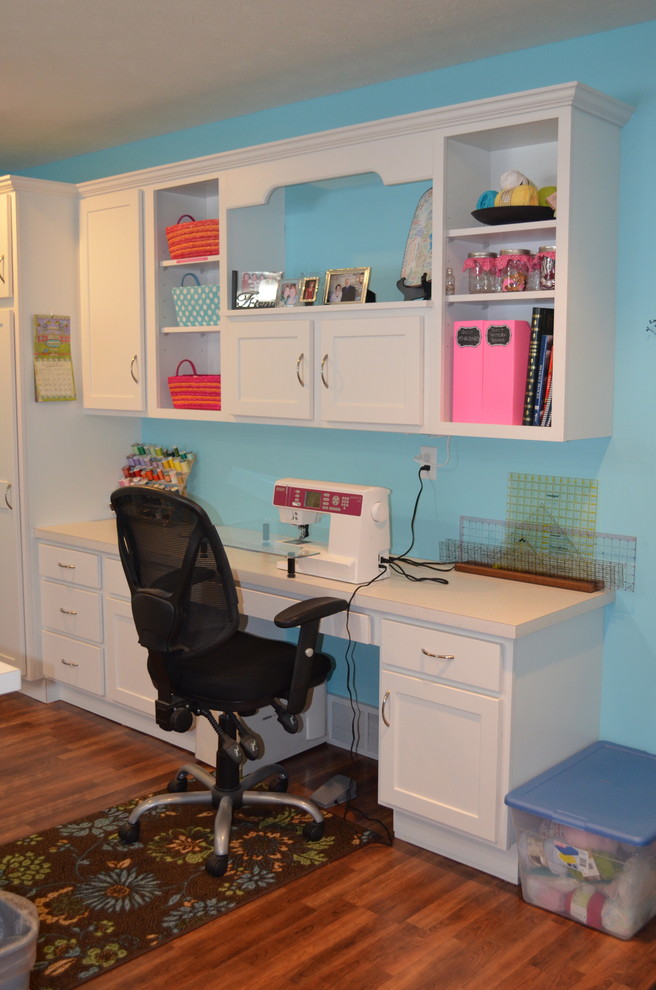 Foto på ett mellanstort funkis hobbyrum, med blå väggar, mellanmörkt trägolv och ett inbyggt skrivbord