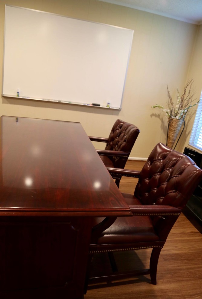 Aménagement d'un grand bureau classique avec un mur beige, un sol en bois brun, un poêle à bois, un bureau indépendant et un sol marron.