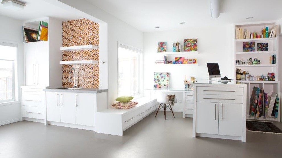 Exempel på ett mellanstort klassiskt hobbyrum, med betonggolv, vita väggar och ett inbyggt skrivbord