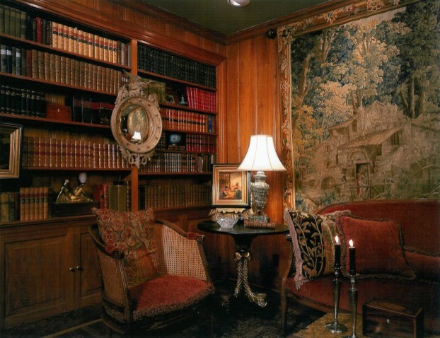 Klassisk inredning av ett stort hemmabibliotek, med bruna väggar, mörkt trägolv och ett fristående skrivbord