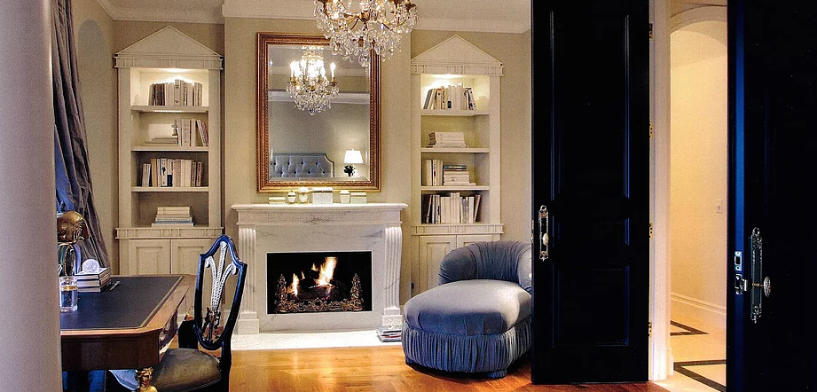 Example of a mid-sized classic freestanding desk medium tone wood floor and brown floor home office library design in Los Angeles with white walls, a standard fireplace and a plaster fireplace