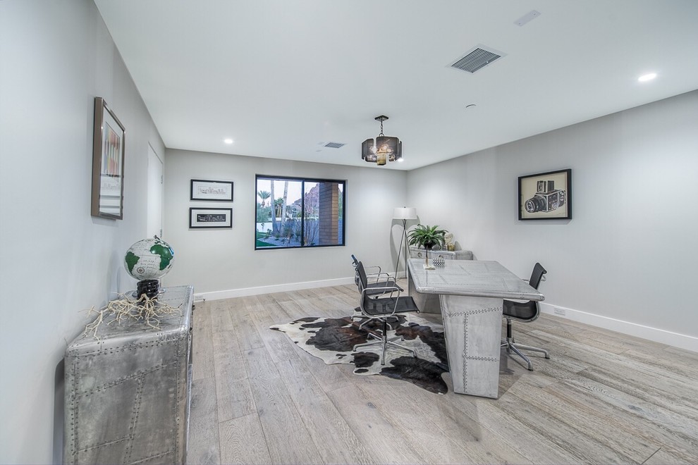 Modelo de despacho actual de tamaño medio con paredes grises, suelo de madera clara y escritorio independiente