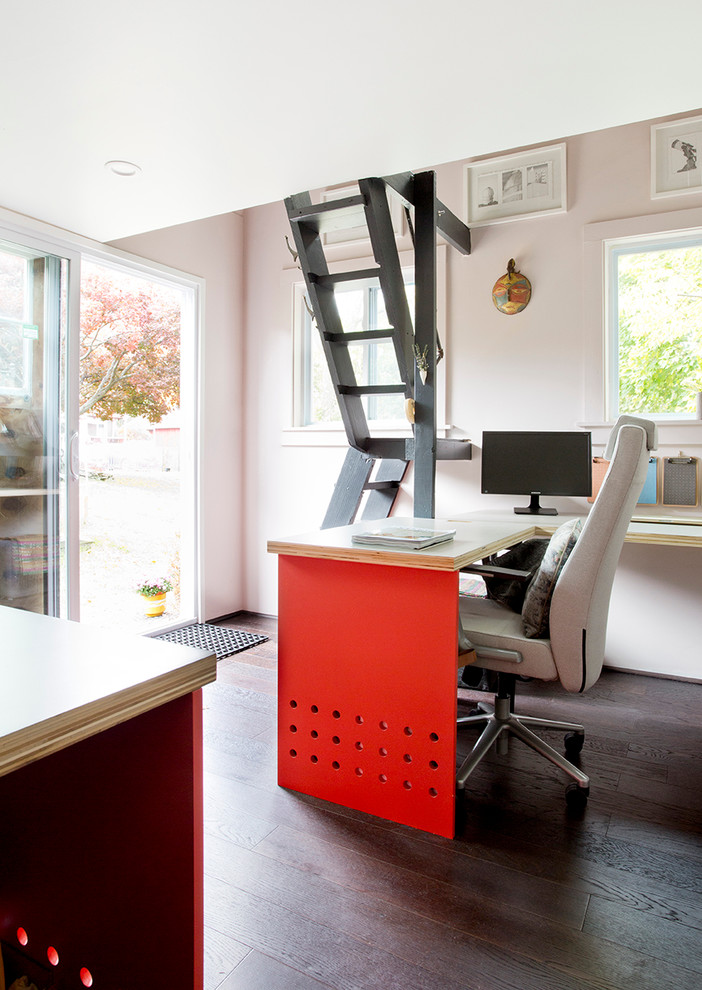 Foto di un piccolo studio moderno con libreria, pareti rosa, parquet scuro e scrivania incassata