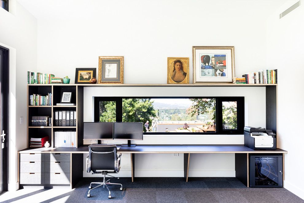 Diseño de despacho contemporáneo grande con paredes blancas, escritorio empotrado y suelo gris