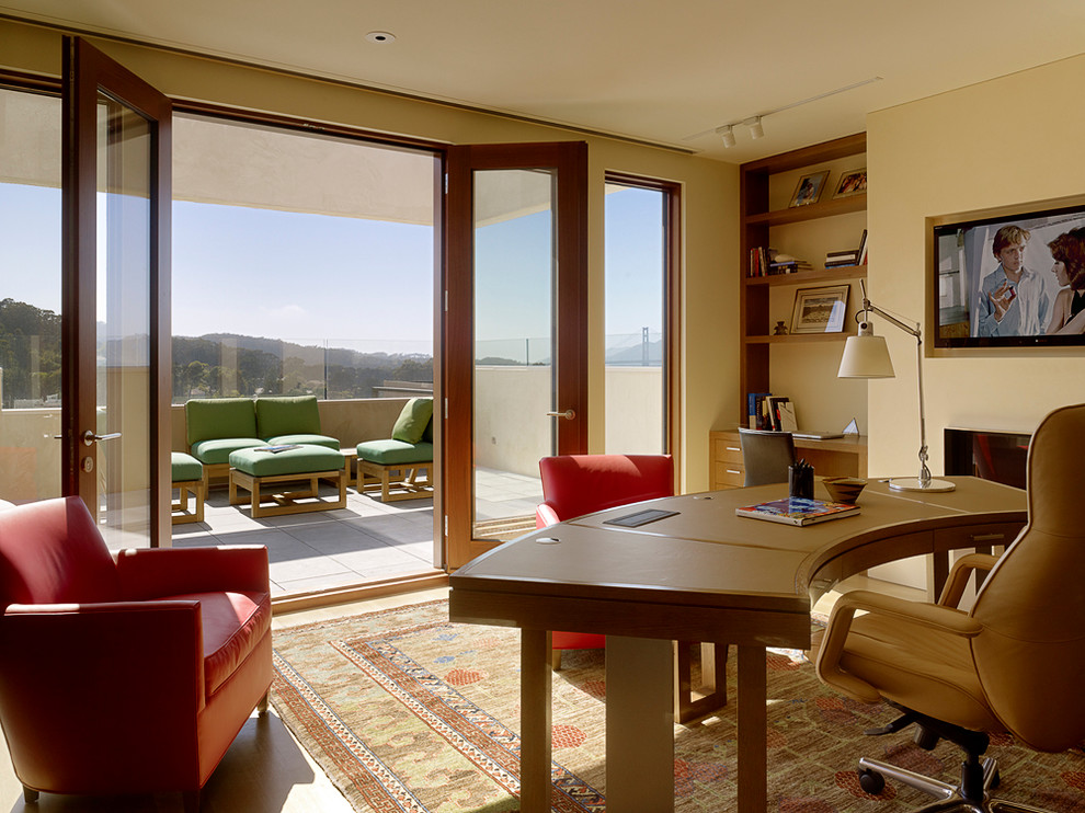 Foto de despacho minimalista grande sin chimenea con paredes beige, suelo de madera clara y escritorio independiente