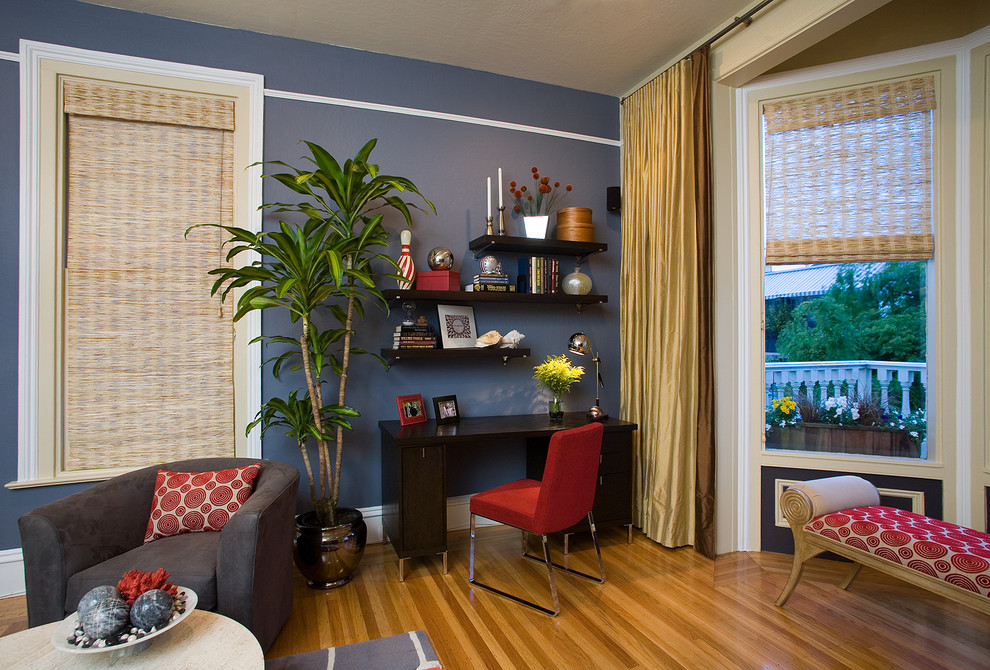 Modelo de despacho actual de tamaño medio sin chimenea con paredes azules, suelo de madera clara, escritorio independiente y suelo azul