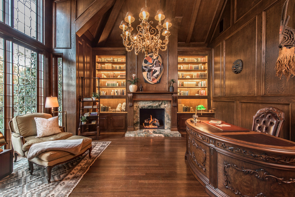 This is an example of a traditional home office in Los Angeles with brown walls, dark hardwood flooring, a standard fireplace, a stone fireplace surround and a chimney breast.
