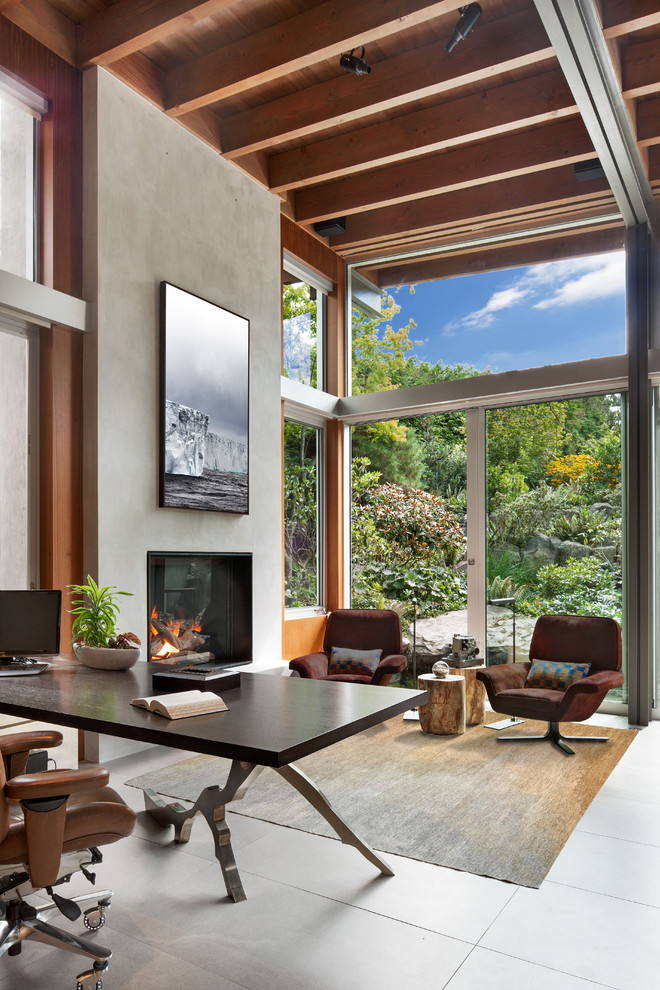 Источник вдохновения для домашнего уюта: кабинет в современном стиле с серыми стенами, стандартным камином, отдельно стоящим рабочим столом и серым полом